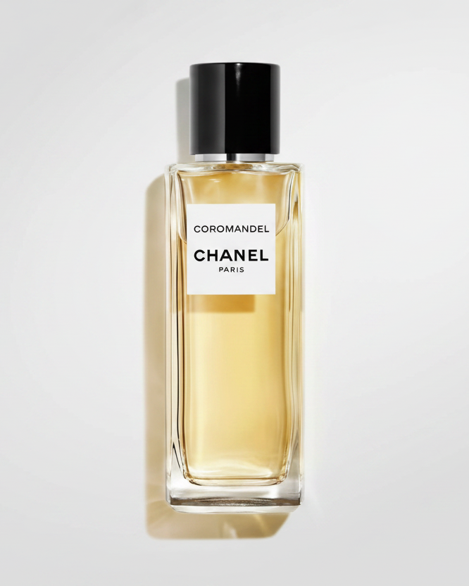 Chanel Coromandel perfume bottle with a black cap and white label, filled with pale golden liquid, on a white background with a soft shadow.