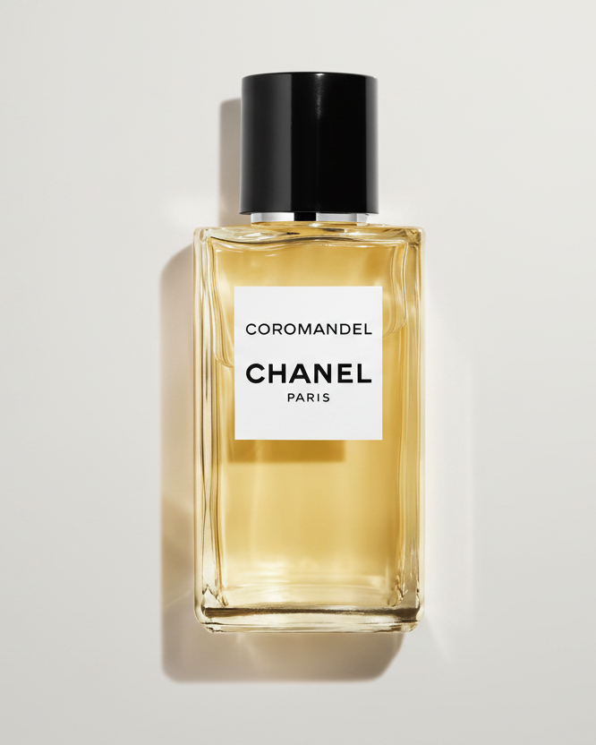 Chanel Coromandel perfume bottle with a black cap and white label, filled with pale golden liquid, on a white background with a soft shadow.