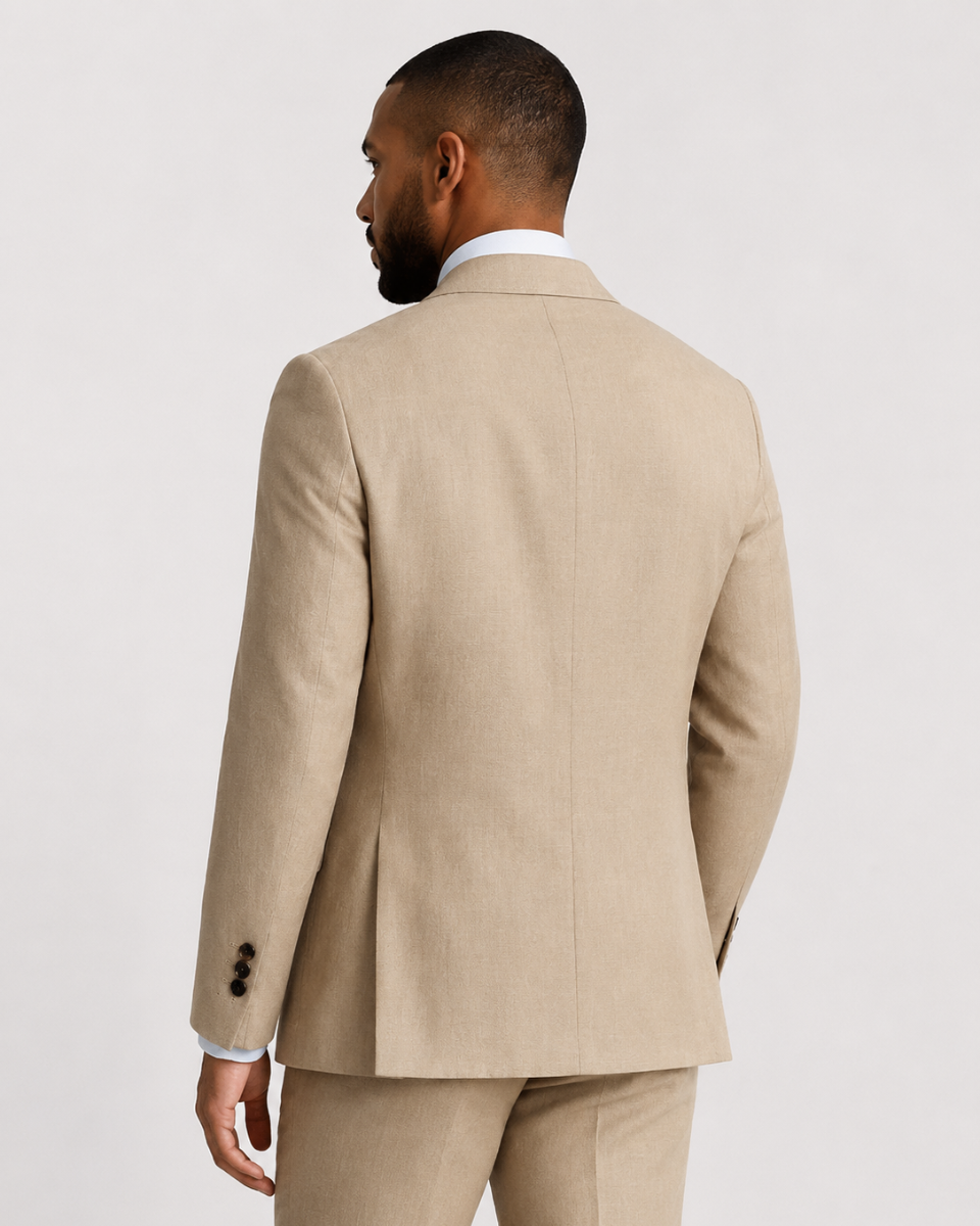 A man shown from the back wearing a light beige suit jacket and matching trousers over a white collared shirt, photographed against a plain light gray studio background.