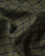 A close-up of a textured woven fabric with a dark olive green base and a subtle navy blue windowpane plaid pattern.