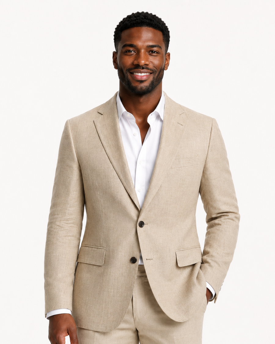 A man wearing a light beige linen suit with a white dress shirt, standing against a plain white studio background.