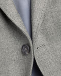 Close-up of a gray textured fabric with a button and visible stitching detail.