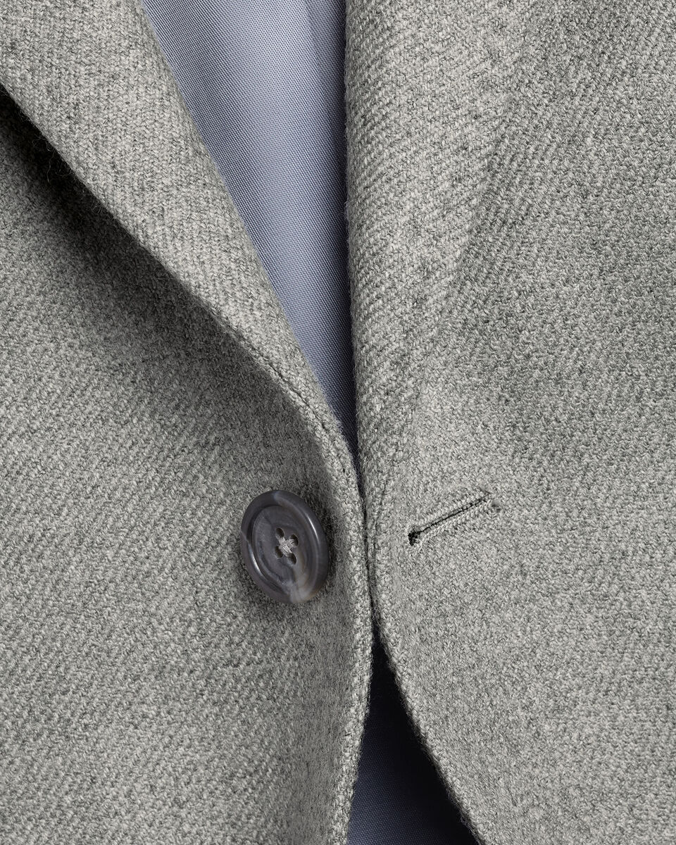 Close-up of a gray textured fabric with a button and visible stitching detail.