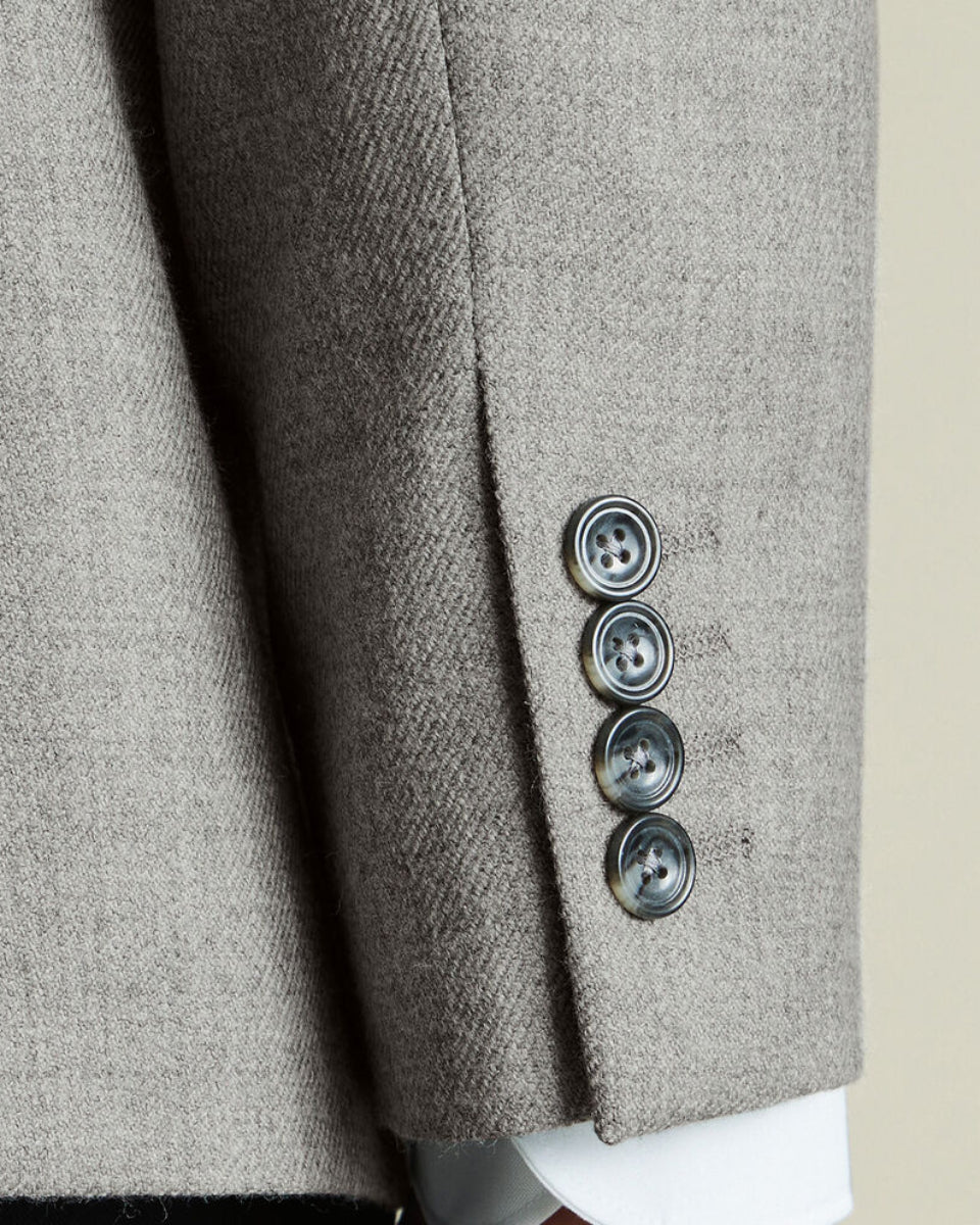 Close-up of a gray textured blazer with three buttons on a neutral background