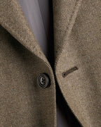 Close-up of a brown textured blazer with a button on a gray background