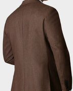 Man wearing a brown coat against a beige background