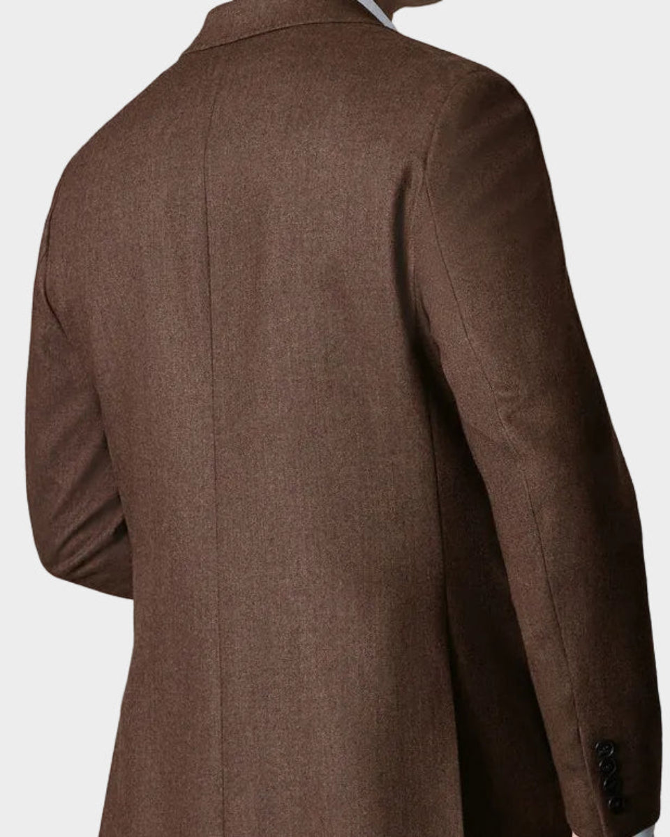 Man wearing a brown coat against a beige background