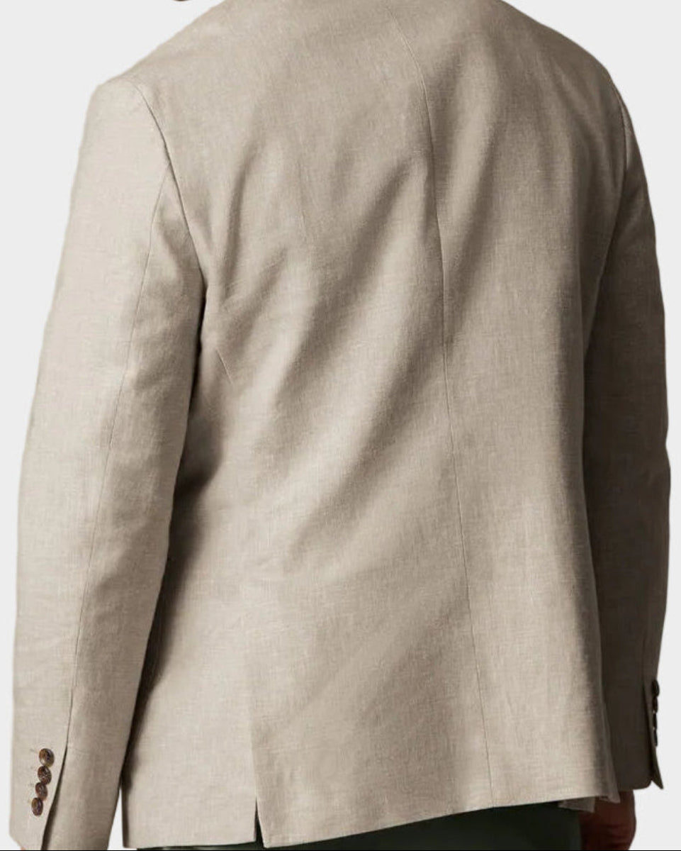 A man shown from the back wearing a light beige linen-blend blazer and olive green trousers, photographed against a solid light beige studio background.