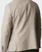 A man shown from the back wearing a light beige linen-blend blazer and olive green trousers, photographed against a solid light beige studio background.