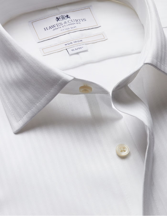 Close-up of a white dress shirt collar with visible buttons and a sewn-in label reading HAWES & CORTIS.