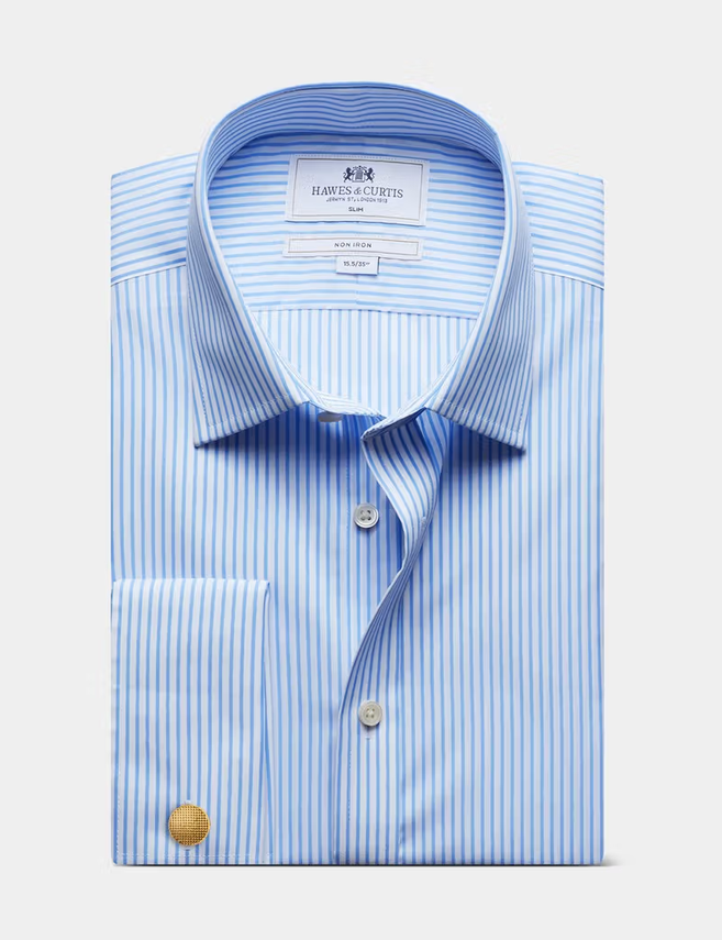 A folded light blue and white striped dress shirt with a pointed collar, button front, and a gold cufflink, shown on a light gray background. The inner neck label reads Martin & Co.
