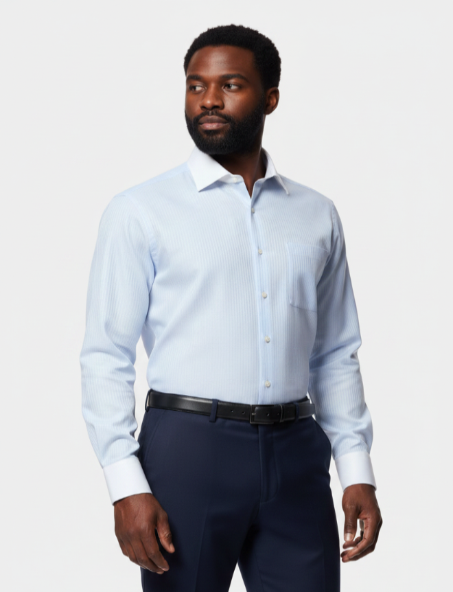A man wearing a light blue long-sleeve dress shirt and dark navy trousers, standing against a light gray studio background.