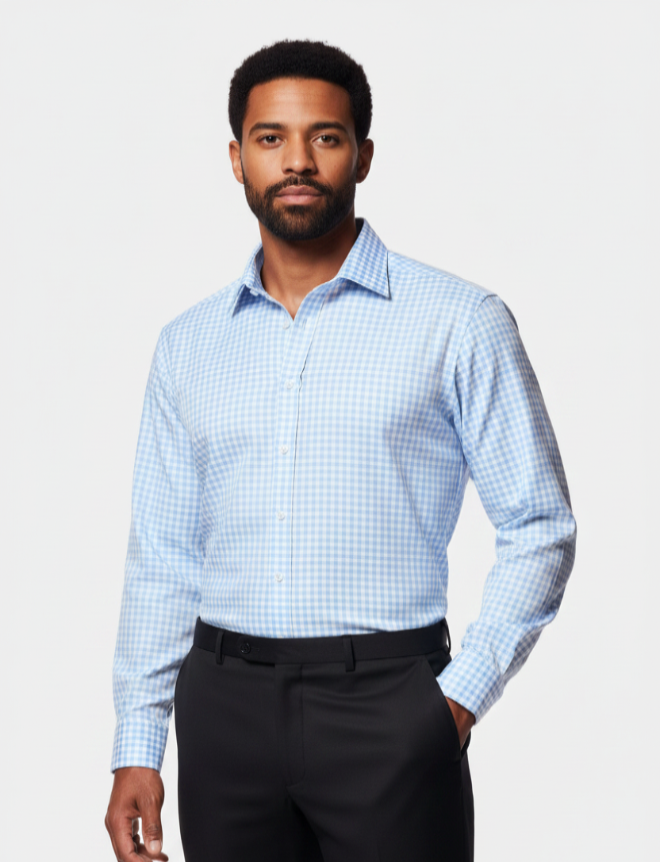 A man wearing a light blue and white gingham long-sleeve dress shirt with black trousers, standing against a light gray studio background.