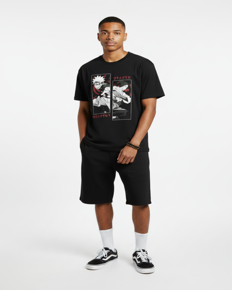 A man modeling a black graphic t-shirt and matching black shorts, styled with white socks and black-and-white sneakers, standing against a textured gray wall.
