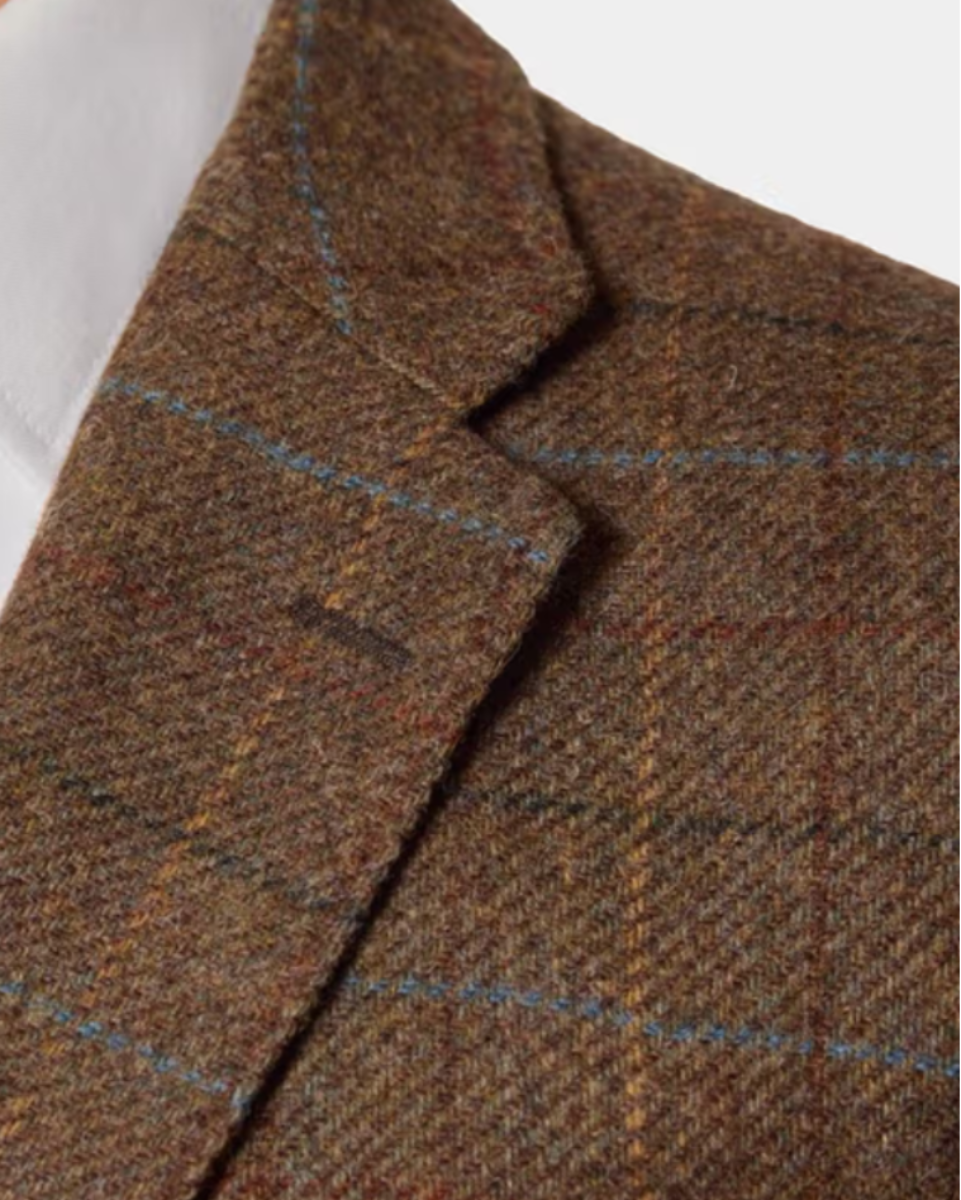 Close-up of a brown tweed blazer with a subtle windowpane check pattern, worn over a white collared shirt.
