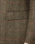 Close-up of a herringbone tweed fabric with a windowpane check pattern in brown, beige, and muted red.