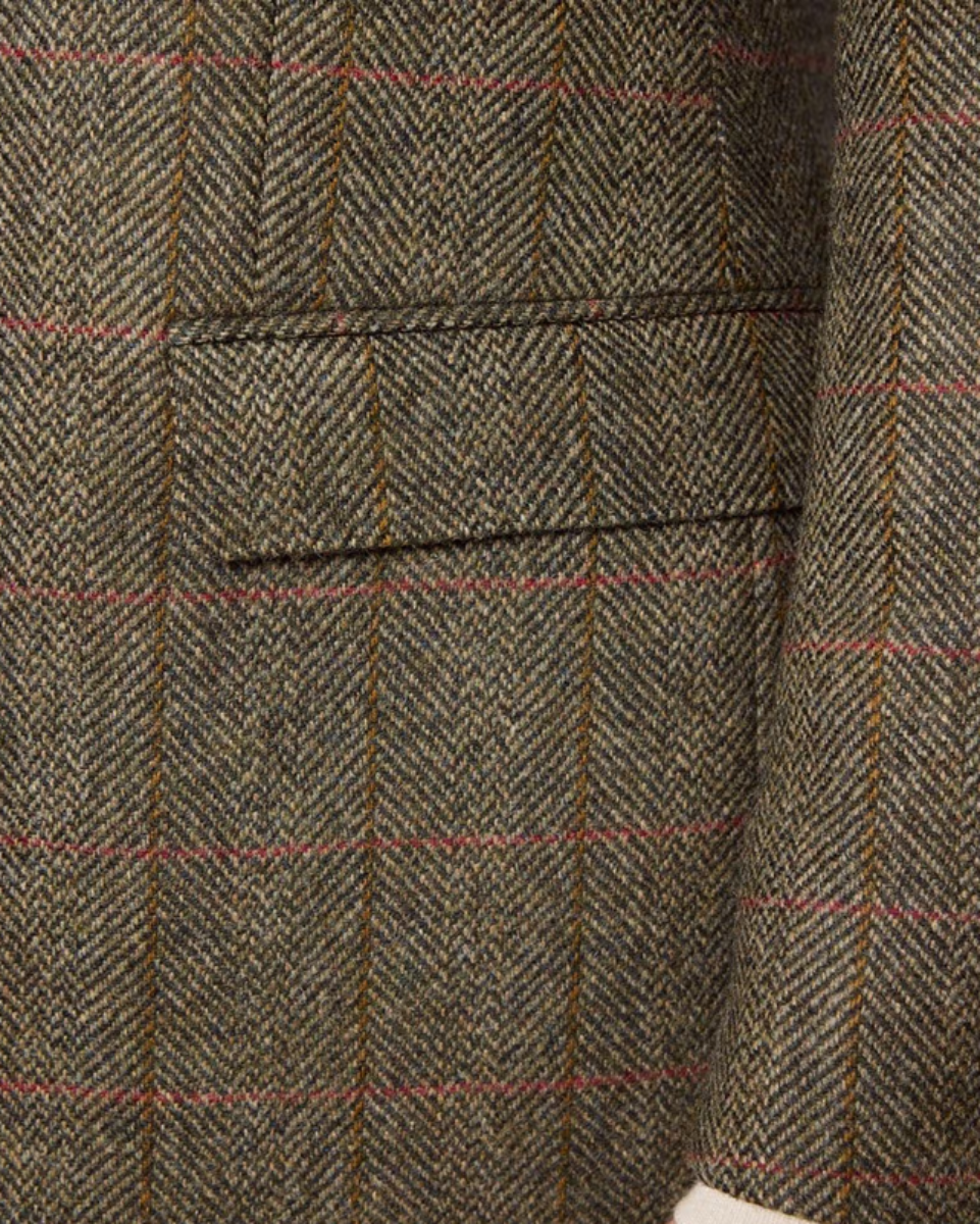 Close-up of a herringbone tweed fabric with a windowpane check pattern in brown, beige, and muted red.