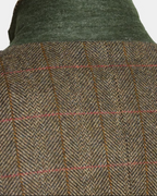 Close-up of a textured herringbone tweed jacket with a green corduroy collar on a mannequin.