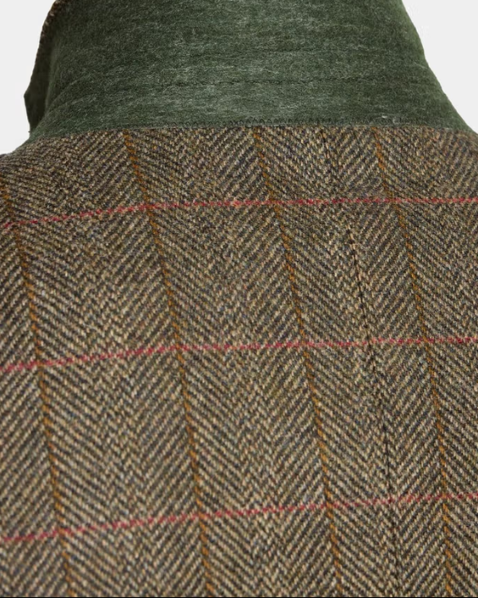 Close-up of a textured herringbone tweed jacket with a green corduroy collar on a mannequin.