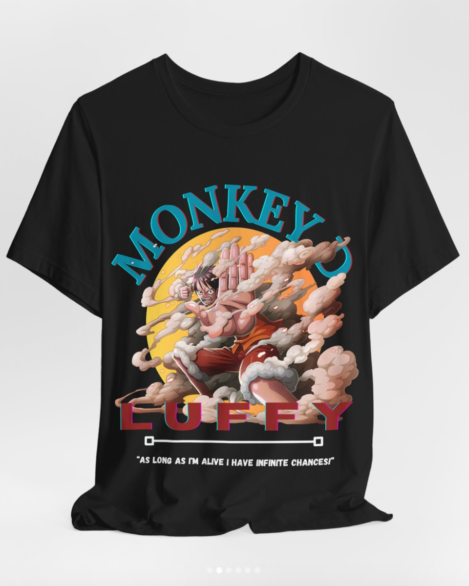 A black short-sleeve graphic t-shirt featuring a colorful print of Monkey Luffy from One Piece. The graphic includes the words 'MONKEY LUFFY' in stylized blue and red lettering, with Monkey Luffy depicted in the center against a yellow sun and clouds.