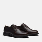 A pair of dark brown leather lace-up dress shoes with a low stacked heel, shown from a three-quarters angle on a light gray background.