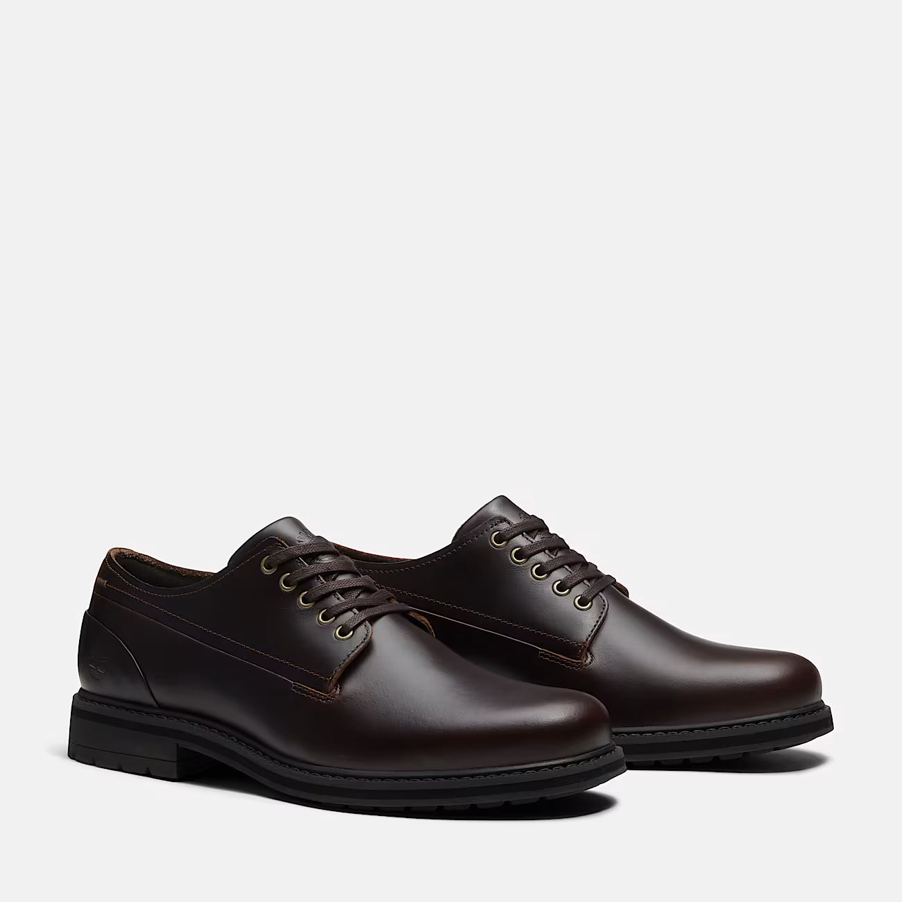 A pair of dark brown leather lace-up dress shoes with a low stacked heel, shown from a three-quarters angle on a light gray background.